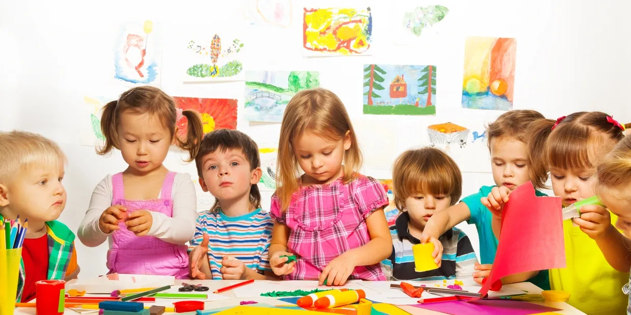 A group of children sitting at a table with art supplies.